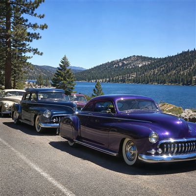 Classic cars lined up at a lakeside car show
